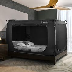 a bed that is in the middle of a room with a fan on top of it