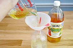 someone is pouring some liquid into a pitcher and another bottle on a wooden counter top