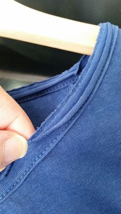 a person's hand on top of a blue t - shirt that is folded up