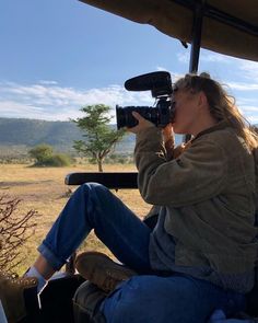 a woman sitting in the back of a truck taking pictures