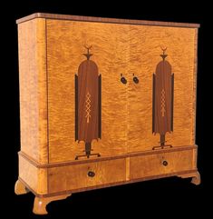 an old fashioned wooden cabinet with two doors and carvings on the front, sitting against a black background