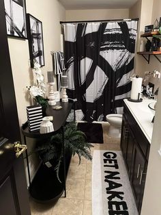 a bathroom with black and white decor on the shower curtain, toilet seat cover and rug