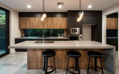 a kitchen with two stools next to an island counter top and three lights hanging from the ceiling