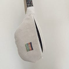 a white purse hanging from a hook on a wall with an animal print lining it