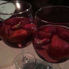 two wine glasses filled with red liquid and strawberries