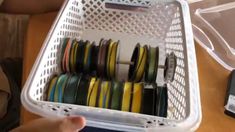 a person holding a container filled with lots of different colored ribbons