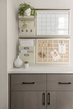 a desk with drawers and office supplies on the top, along with a plant in a white vase