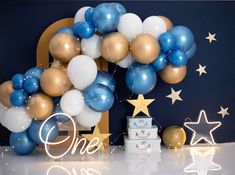 balloons and stars are on the table for a one - year birthday party with blue, gold and white decorations