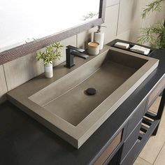 a bathroom sink sitting under a mirror next to a counter top with plants on it