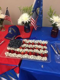 an american flag cake on a table with flowers and other patriotic items around the table