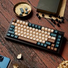 a computer keyboard sitting on top of a wooden table next to a phone and other items