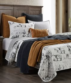 a bed covered in blankets and pillows with animals on them