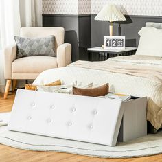 a white bed sitting next to a chair and a table on top of a hard wood floor