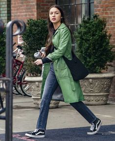 a woman is walking down the street with her hand in her pocket and carrying a black purse