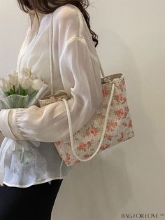 a woman holding a flower bouquet in her right hand while wearing a white blouse and black pants