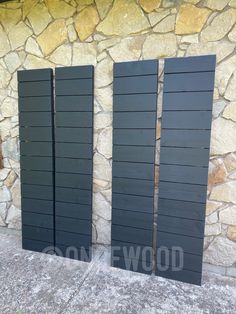 three black shutters sitting next to a stone wall