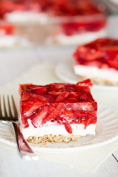 a piece of cheesecake with raspberry topping on a plate next to some strawberries