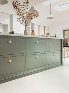 a green cabinet with brass knobs in a white kitchen and an island countertop