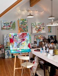 an artist's studio with paintings on the wall and stools in front of it