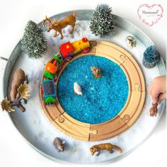 a child's hand is holding a toy train set on top of a table