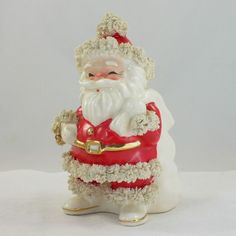 a white and red santa clause figurine sitting on top of a white table