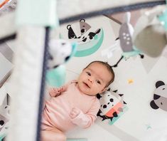 a baby is laying in a crib with animals on the wall behind it and smiling at the camera