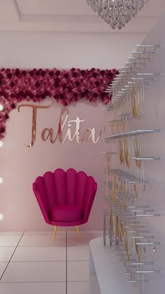 a pink chair sitting in front of a wall with gold letters on it and a chandelier hanging from the ceiling