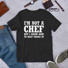 Spice up your wardrobe with our "I'M NOT A CHEF, BUT I KNOW HOW TO HEAT THINGS UP" t-shirt! Perfect for food lovers, home cooks, or anyone who loves to add a little heat to their life. This witty tee is a fun way to show off your sense of humor, whether you're in the kitchen or out and about. It is a great gift for chefs, food enthusiasts, or anyone who enjoys playful puns. Turn up the heat with this stylish and humorous t-shirt! you can even wear it as Halloween costume  This t-shirt is everything you've dreamed of and more. It feels soft and lightweight, with the right amount of stretch. It's comfortable and flattering for all.  * 100% combed and ring-spun cotton (Heather colors contain polyester) * Fabric weight: 4.2 oz./yd.² (142 g/m²) * Pre-shrunk fabric * Side-seamed construction * S Cooking Puns, Cooking Shirt, Funny Cooking, Cooking Humor, Chef Gifts, A Chef, Costume Halloween, Birthday Shirts, Puns