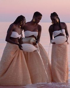 three women standing in the water at sunset