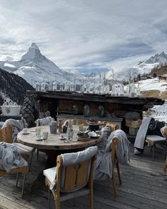 an outdoor dining area with mountain view in the backgrounnd, and wooden table surrounded by chairs