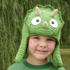 a young boy wearing a green crocheted hat with googly eyes and horns