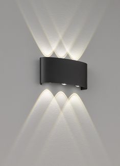 a wall mounted light on the side of a white wall with three lights in it