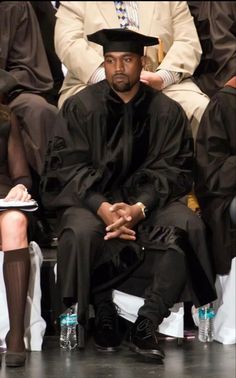 a man in a black outfit and hat sitting down