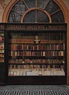 an old book store with many books on the shelves and in front of it is a large arched window