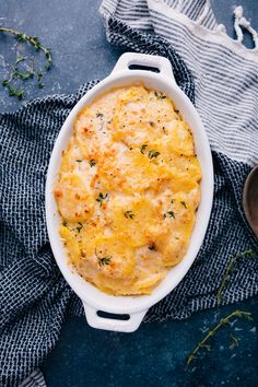 a casserole dish with cheese and herbs in it on a blue table cloth