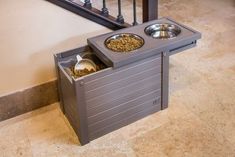 an elevated dog food station with two bowls in it