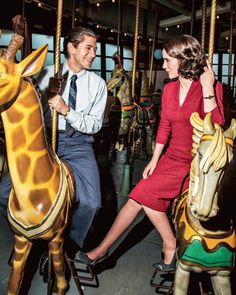 a man and woman riding on a merry go round with giraffes in the background