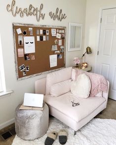 a living room with a pink couch, white rugs and a bulletin board on the wall