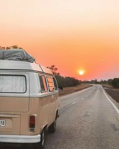 an old vw bus is parked on the side of the road at sunset or dawn