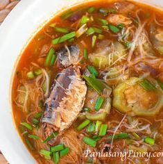 a white bowl filled with meat and vegetable soup on top of a woven place mat