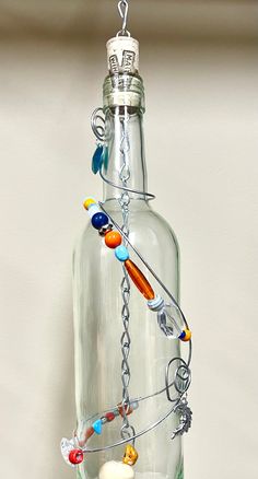 a glass bottle filled with lots of beads and chains hanging from it's side