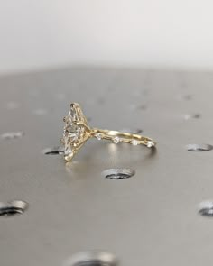 a diamond ring sitting on top of a metal surface with drops of water around it