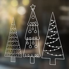 three christmas trees drawn on a glass window