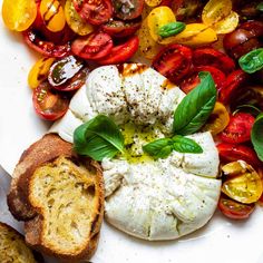 a plate with bread, tomatoes and mozzarella on it next to some basil