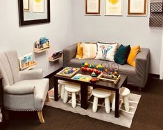 a living room filled with furniture and pictures on the wall next to a coffee table