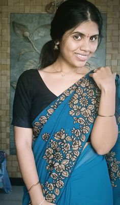 a woman in a blue and black sari is posing for the camera with her hand on her shoulder