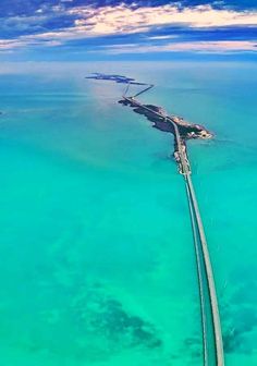 an aerial view of a bridge in the middle of the ocean with clear blue water