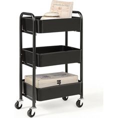 a black cart with three trays on wheels and an open book in the middle