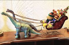 a toy dinosaur pulling a sleigh with stuffed animals on it's back