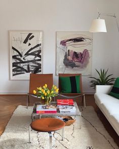 a living room filled with furniture and paintings on the wall above it's coffee table